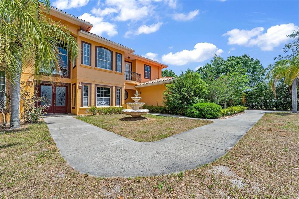 A two-story orange stucco house features a front fountain, a paved walkway, and palm trees — 13161 LAKE BUTLER BOULEVARD, WINDERMERE, FL