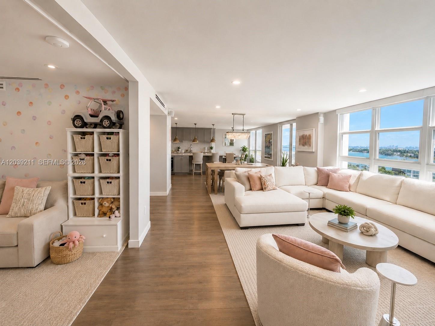 An open-concept living and dining area features a white sectional, wood flooring, and water views — 9 Island Ave # 1114, Miami Beach FL 33139, MIAMI BEACH, FL