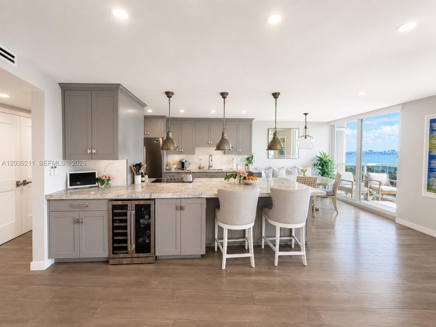 A modern kitchen features gray cabinetry, a marble-topped island, and a view of the ocean — 9 Island Ave # 1114, Miami Beach FL 33139, MIAMI BEACH, FL
