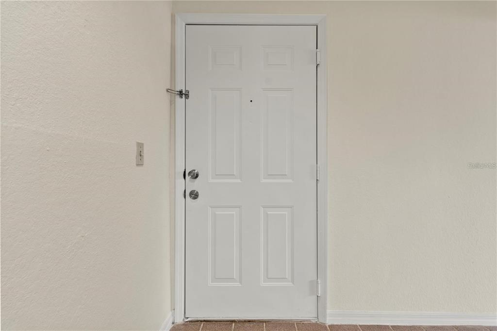 A white six-panel door with a security latch is set in a plain wall — 7330 WESTPOINTE BOULEVARD UNIT 421, ORLANDO, FL