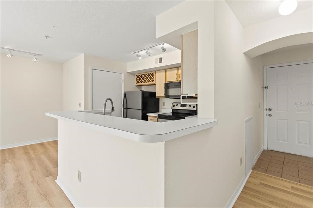 A kitchen with light wood cabinets, stainless steel appliances, and a breakfast bar counter — 7330 WESTPOINTE BOULEVARD UNIT 421, ORLANDO, FL