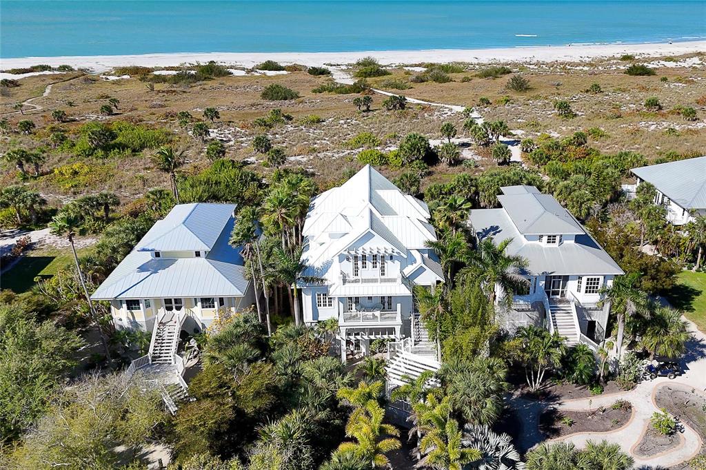 An aerial view shows three coastal houses nestled among palm trees near a sandy beach — 7320 PALM ISLAND DRIVE, PLACIDA, FL