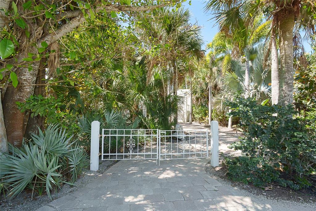A white metal gate stands at the entrance of a stone path surrounded by trees — 7320 PALM ISLAND DRIVE, PLACIDA, FL