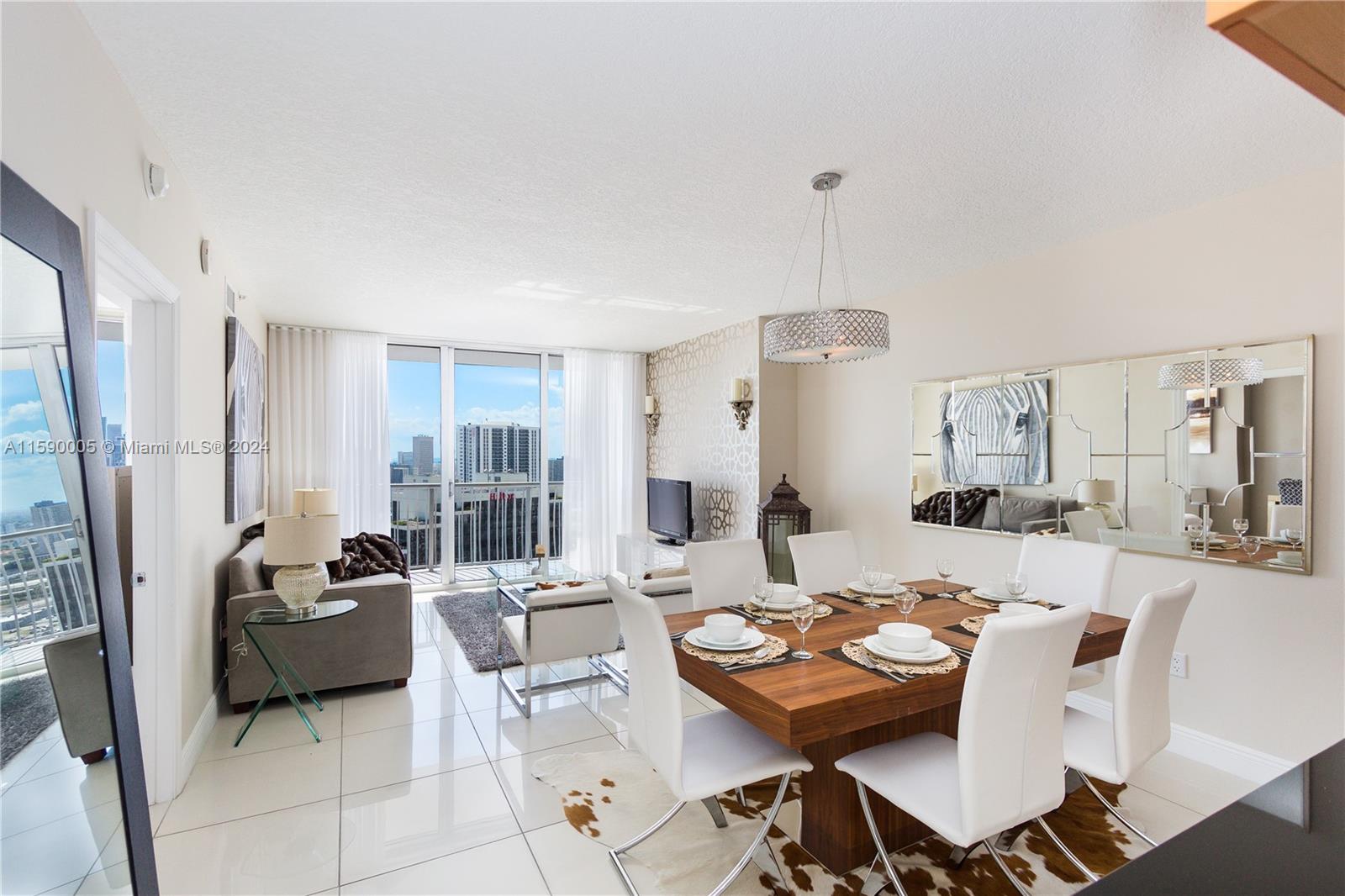 A modern dining and living area features white tile floors, a wooden table, and balcony views — 1750 N Bayshore Dr # 3512, Miami FL 33132, MIAMI, FL
