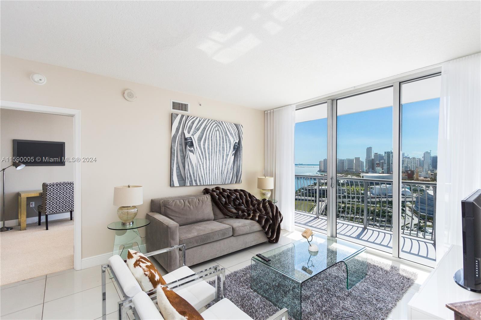 A living room features a grey sofa, glass coffee table, and a balcony with city views — 1750 N Bayshore Dr # 3512, Miami FL 33132, MIAMI, FL