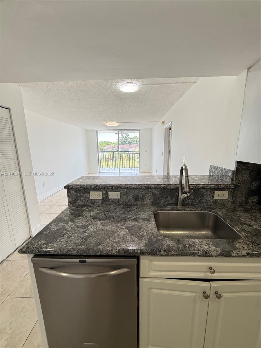 A kitchen features granite countertops, a stainless steel sink, and a view toward a balcony — 14155 SW 87th St # E410, Miami FL 33183, MIAMI, FL
