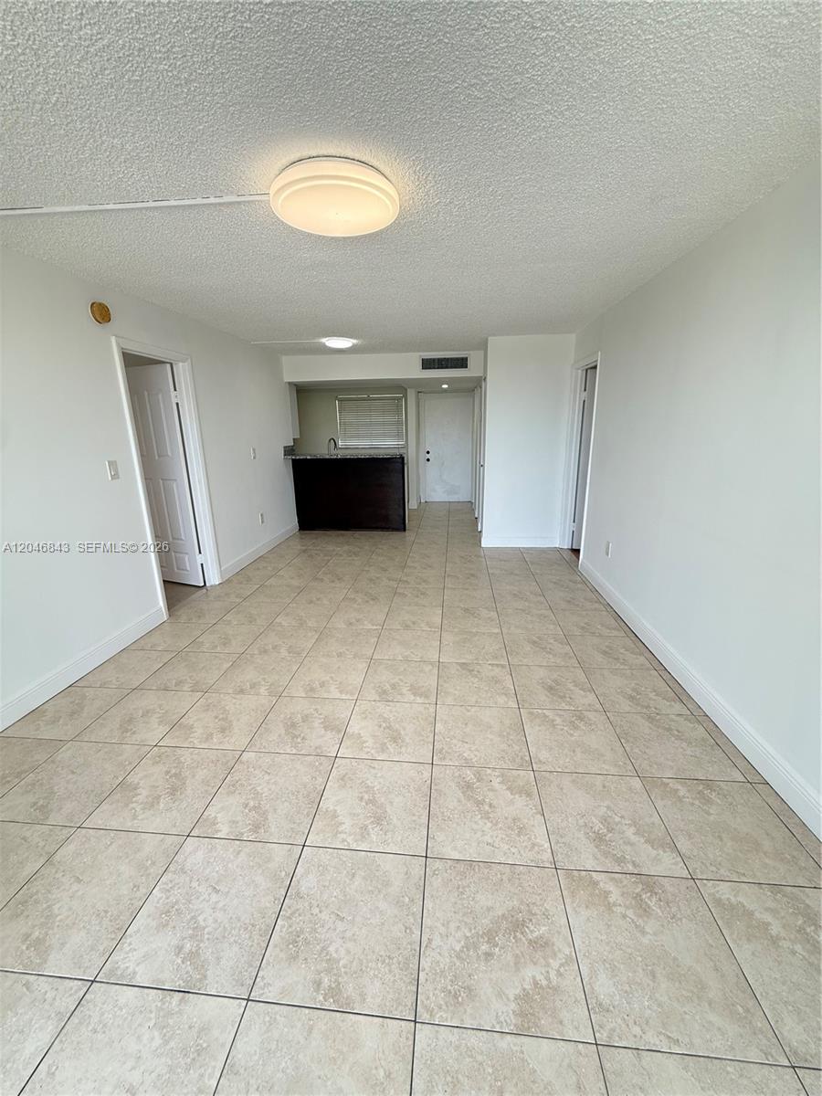 This room features light-colored tile flooring, white walls, and a dark kitchen island — 14155 SW 87th St # E410, Miami FL 33183, MIAMI, FL