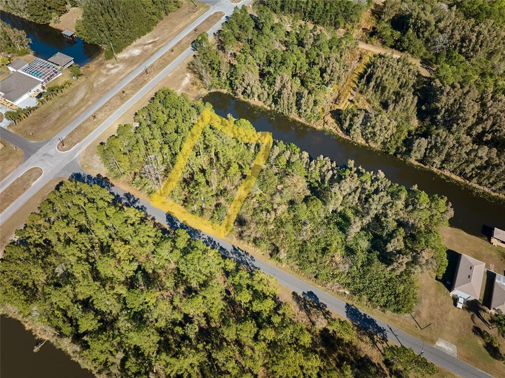 An aerial view shows a wooded, rectangular vacant lot bordered by a road and canal — 0 LANTANA DRIVE S, INDIAN LAKE ESTATES, FL