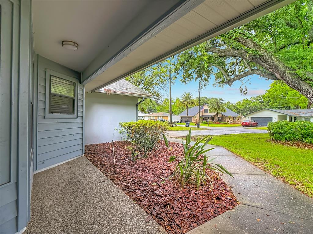 A view from a covered porch looking out toward a suburban street and neighboring houses — 109 SOUTH COURT, AUBURNDALE, FL