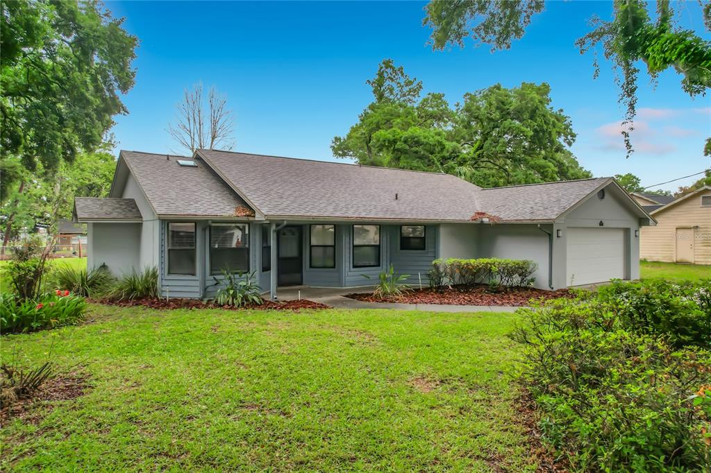 A single-story gray house with a shingled roof, front lawn, and attached garage — 109 SOUTH COURT, AUBURNDALE, FL