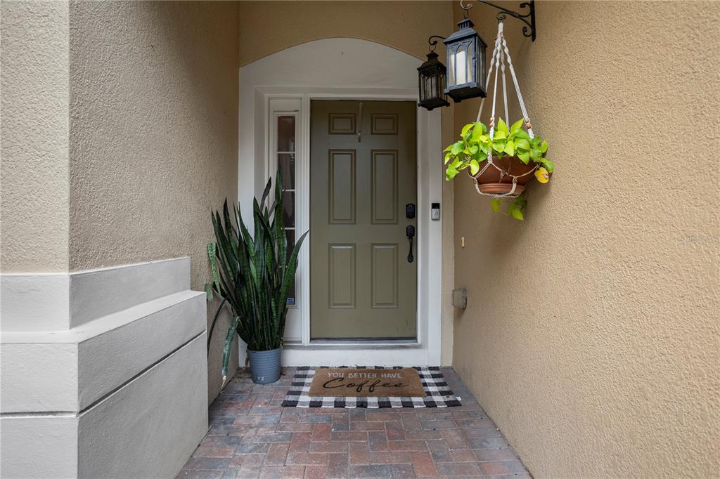 An exterior entryway features a green door, a potted plant, and a coffee-themed doormat — 3401 SHALLOT DRIVE UNIT 103, ORLANDO, FL