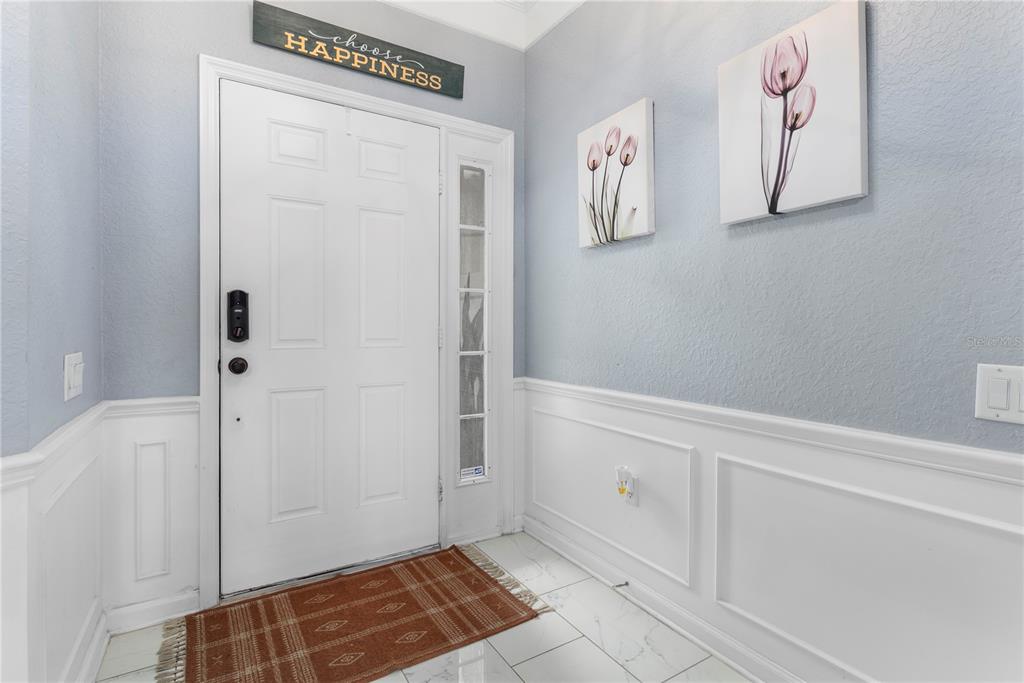 An entryway features a white front door, light blue walls, wainscoting, and tile flooring — 3401 SHALLOT DRIVE UNIT 103, ORLANDO, FL