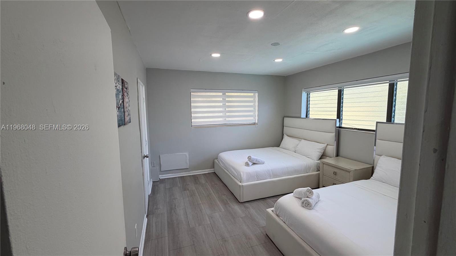 A bedroom features two white platform beds, light gray walls, and wood-look flooring — 10004 E Bay Harbor Dr # 10, Bay Harbor Islands FL 33154, BAY HARBOR ISLANDS, FL