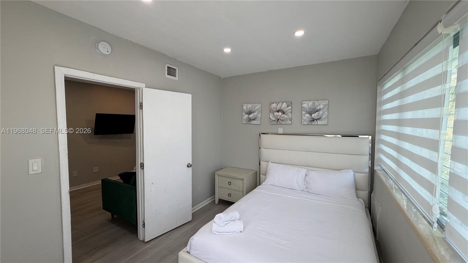 A bedroom features a white upholstered headboard, a nightstand, and a doorway to another room — 10004 E Bay Harbor Dr # 10, Bay Harbor Islands FL 33154, BAY HARBOR ISLANDS, FL