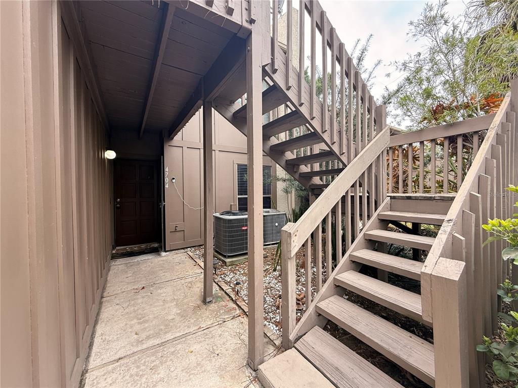 An exterior view shows a brown wooden staircase leading to an upper level near a doorway — 4704 JASMINE CREEK LANE UNIT 1508A, ORLANDO, FL