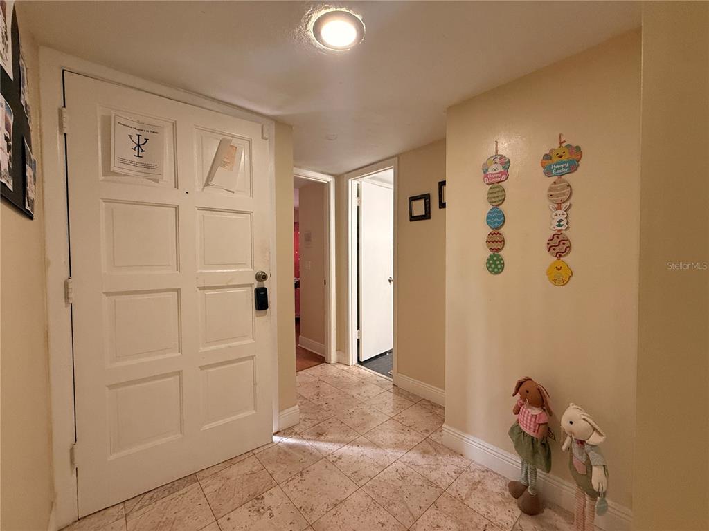 An entryway with a white door, tiled floor, and Easter-themed wall decorations — 4704 JASMINE CREEK LANE UNIT 1508A, ORLANDO, FL