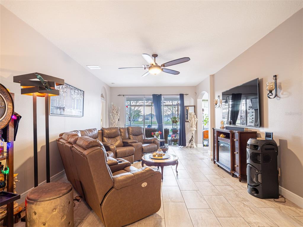 A living room features a brown leather sectional, a ceiling fan, and a wall-mounted television — 10196 ANDOVER POINT CIRCLE, ORLANDO, FL