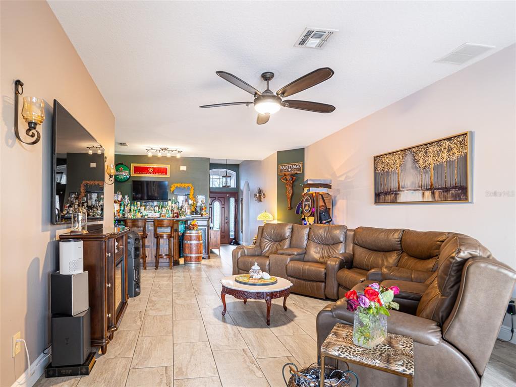 A living room features a brown leather sectional, a bar area, and tile flooring — 10196 ANDOVER POINT CIRCLE, ORLANDO, FL