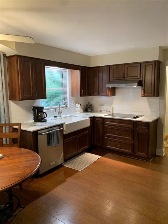 A kitchen features dark wood cabinets, white countertops, a farmhouse sink, and stainless steel appliances — 1501 INDIANA AVENUE, PALM HARBOR, FL