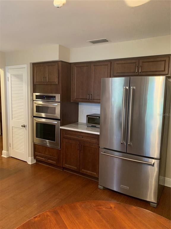 A kitchen features dark wood cabinets, stainless steel appliances, and wood flooring — 1501 INDIANA AVENUE, PALM HARBOR, FL
