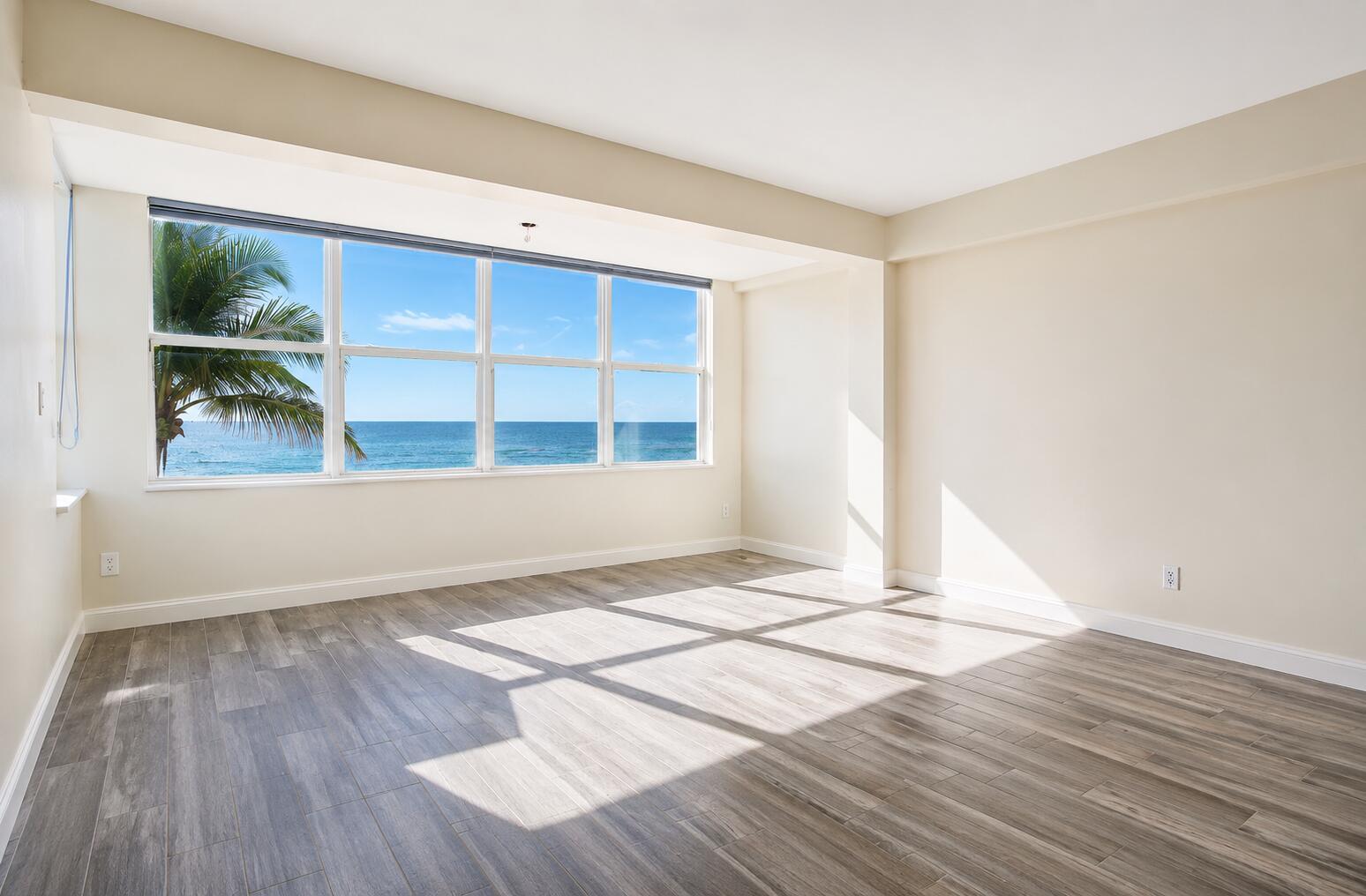 An empty room with light wood-look flooring and large windows overlooking the ocean — 1801 S Surf Road # 2a, Hollywood FL 33019, HOLLYWOOD, FL