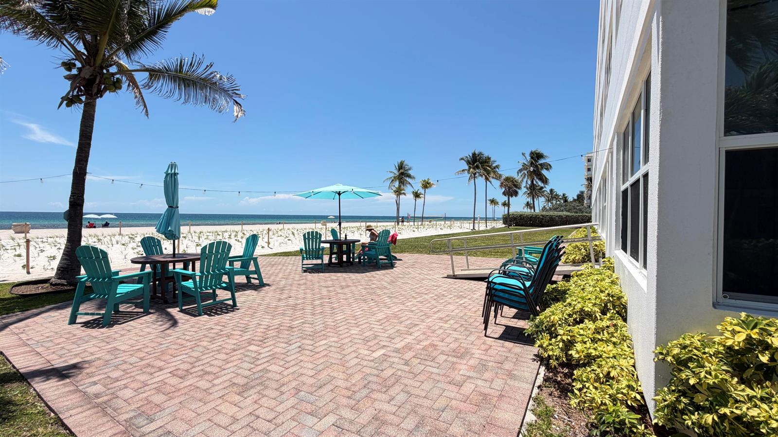 A brick patio with turquoise chairs and umbrellas overlooks a sandy beach and ocean — 1801 S Surf Road # 2a, Hollywood FL 33019, HOLLYWOOD, FL