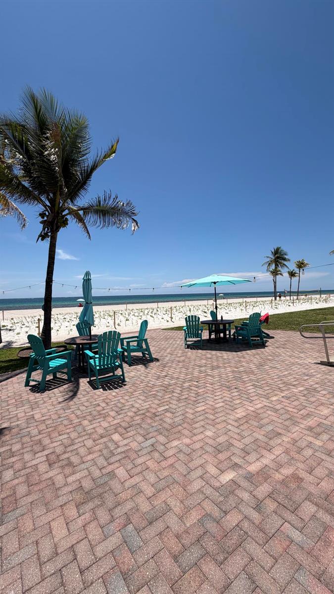 A brick patio features Adirondack chairs and umbrellas overlooking a sandy beach and the ocean — 1801 S Surf Road # 2a, Hollywood FL 33019, HOLLYWOOD, FL
