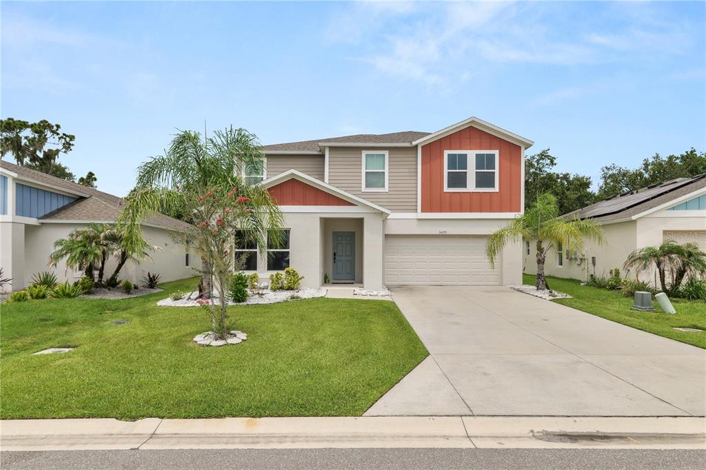 A two-story suburban house features a beige and orange exterior with a two-car garage — 5693 ARLINGTON RIVER DRIVE, LAKELAND, FL