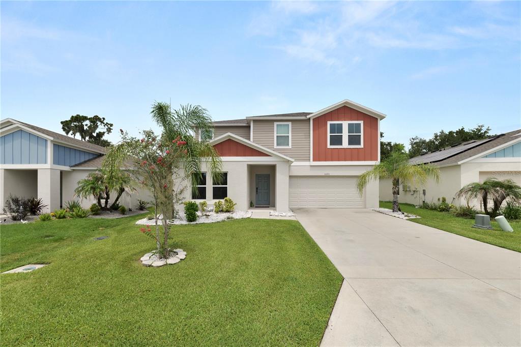 A two-story suburban house features a beige and red exterior with a two-car garage — 5693 ARLINGTON RIVER DRIVE, LAKELAND, FL