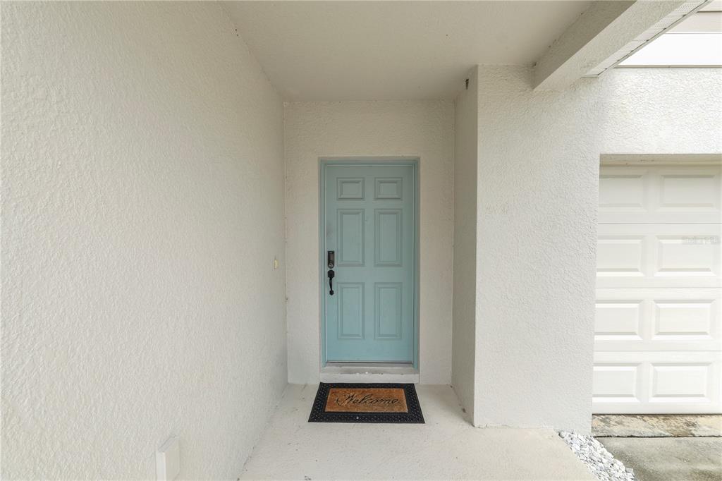 A light blue front door is centered in a covered entryway next to a garage — 5693 ARLINGTON RIVER DRIVE, LAKELAND, FL