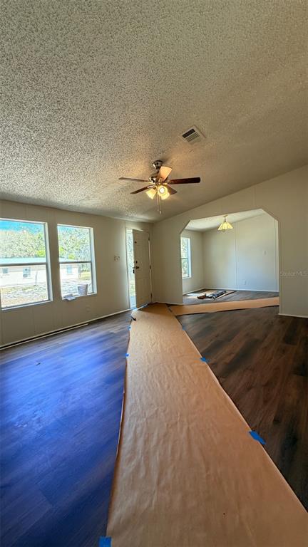 A living room with wood-look flooring, a ceiling fan, and a doorway to another room — 1910 40TH STREET NW, WINTER HAVEN, FL