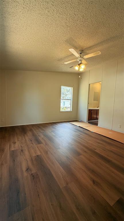 An empty room features wood-look flooring, a ceiling fan, and a doorway leading to a bathroom — 1910 40TH STREET NW, WINTER HAVEN, FL