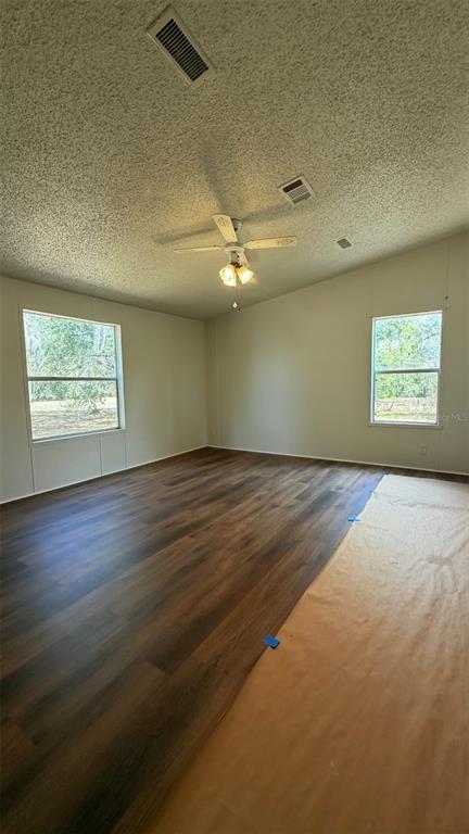 A spacious room features dark wood-look flooring, a ceiling fan, and two windows — 1910 40TH STREET NW, WINTER HAVEN, FL