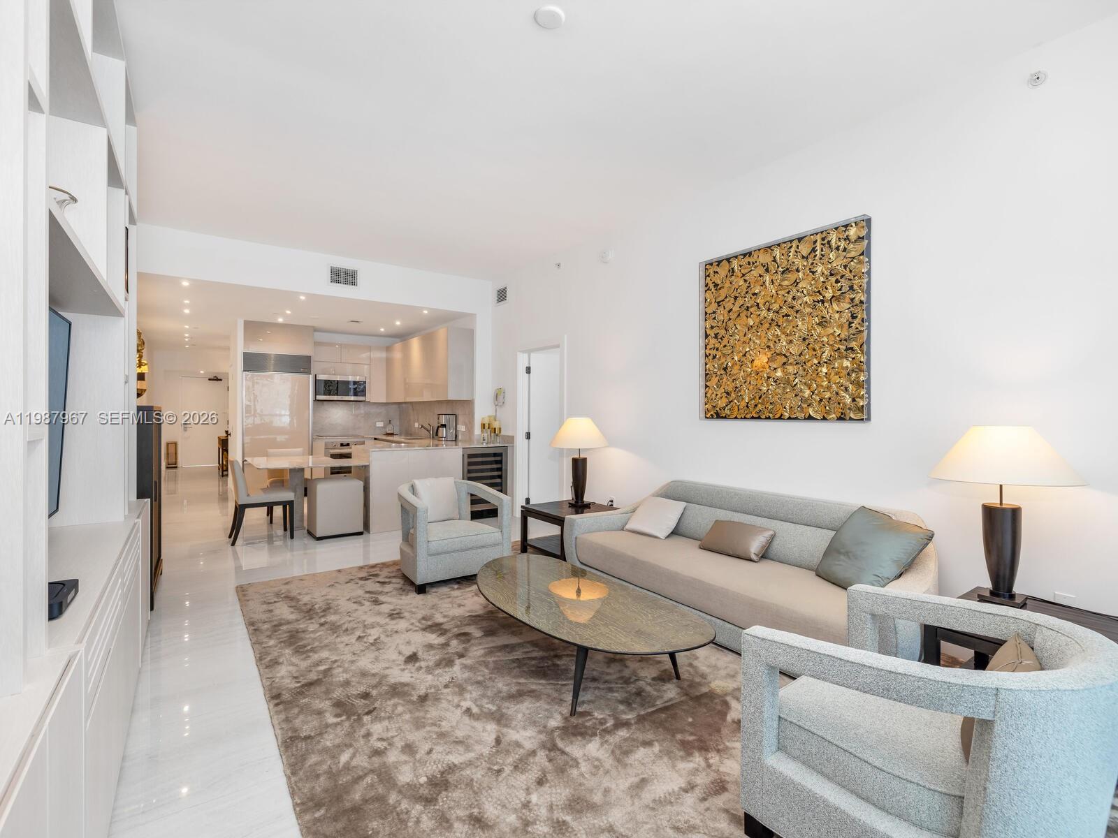 A modern living room with a sofa, armchairs, coffee table, and an open-concept kitchen — 6799 Collins Ave # 501, Miami Beach FL 33141, MIAMI BEACH, FL