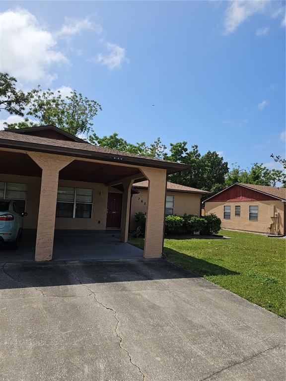 A tan house with a covered carport and a concrete driveway under a blue sky — 7626 GOLDEN GLENN DRIVE, ORLANDO, FL