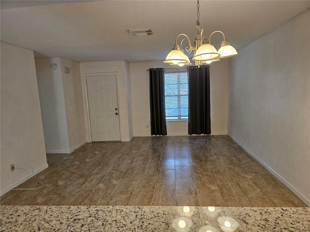 A dining area features tile flooring, a chandelier, and a window with dark curtains — 7626 GOLDEN GLENN DRIVE, ORLANDO, FL