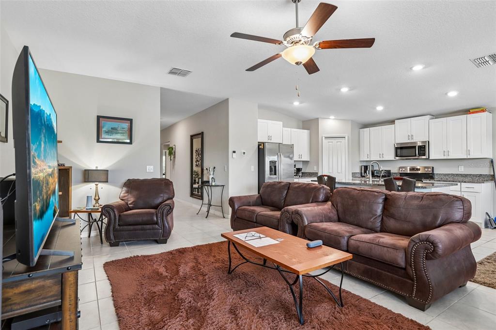 A living room with brown leather furniture, a shag rug, and an open-concept kitchen — 1461 GOLDEN GLOW DRIVE, RUSKIN, FL