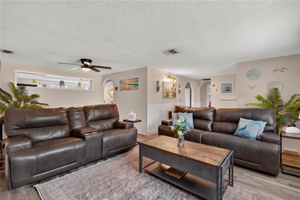 A living room features two dark brown leather sofas, a wooden coffee table, and light flooring — 13129 FILBERT STREET, HUDSON, FL