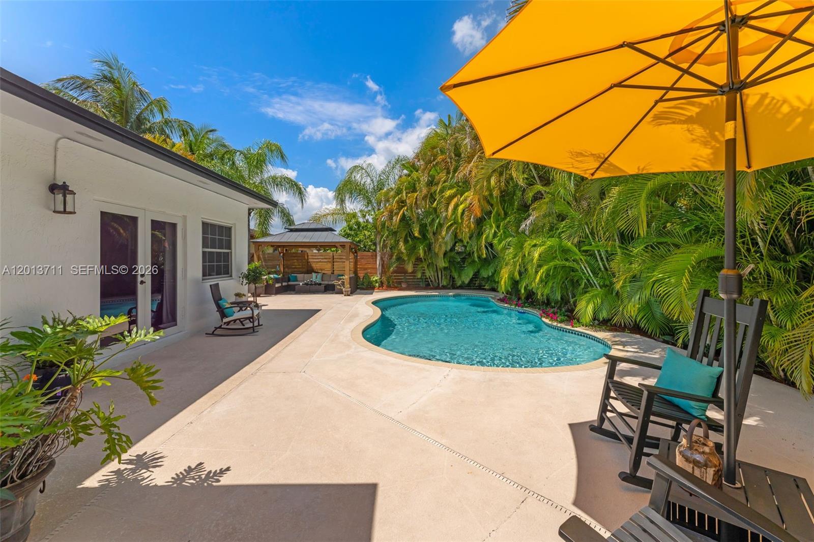 A backyard features a swimming pool, a patio with rocking chairs, and a wooden gazebo — 6651 SW 148th Court, Miami FL 33193, MIAMI, FL