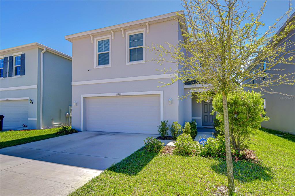 A two-story suburban house with a gray exterior, a garage, and a side yard — 15982 WEATHERED WINDMILL TERRACE, ODESSA, FL