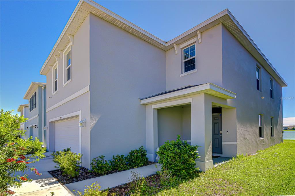 A two-story light gray house with a garage, front porch, and side lawn — 15982 WEATHERED WINDMILL TERRACE, ODESSA, FL