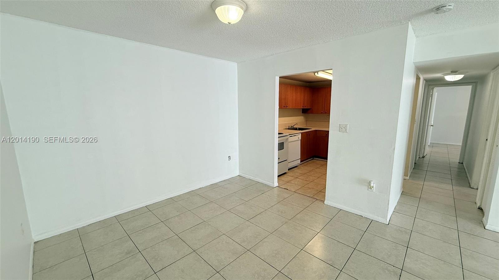 A tiled dining area opens into a kitchen with wood cabinets and white appliances — 415 Executive Center Dr # 203, West Palm Beach FL 33401, WEST PALM BEACH, FL