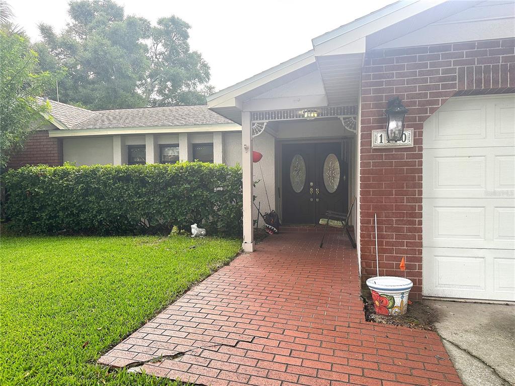 A brick walkway leads to the double front doors of a house with a garage — 1170 WEXFORD DRIVE, PALM HARBOR, FL