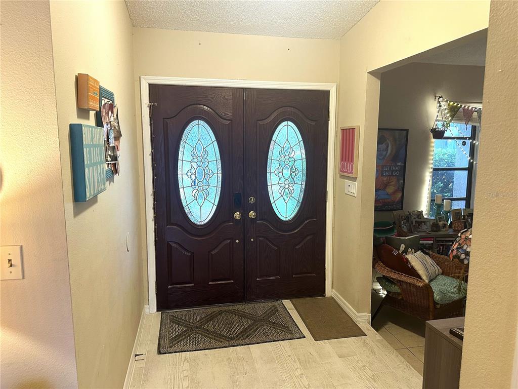 An entryway features double doors with oval glass inserts and light-colored tile flooring — 1170 WEXFORD DRIVE, PALM HARBOR, FL