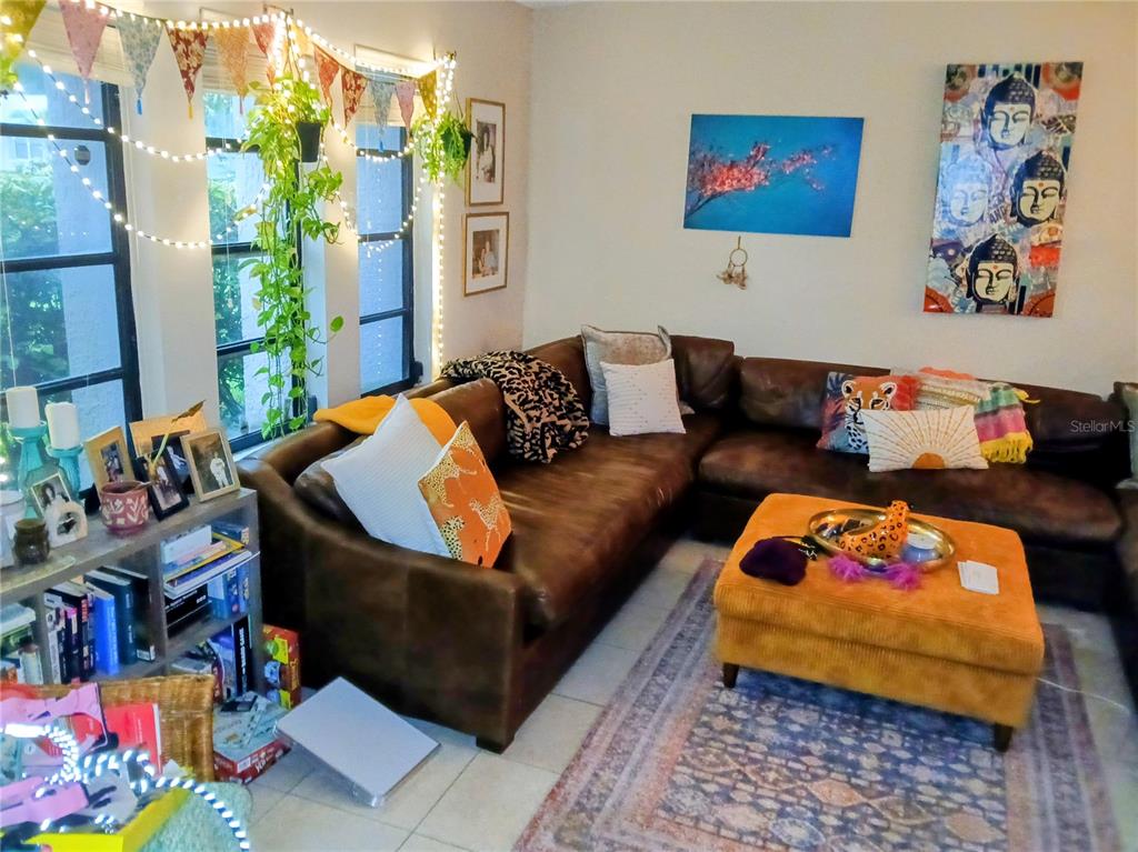A living room features a brown leather sectional, an orange ottoman, and string lights — 1170 WEXFORD DRIVE, PALM HARBOR, FL