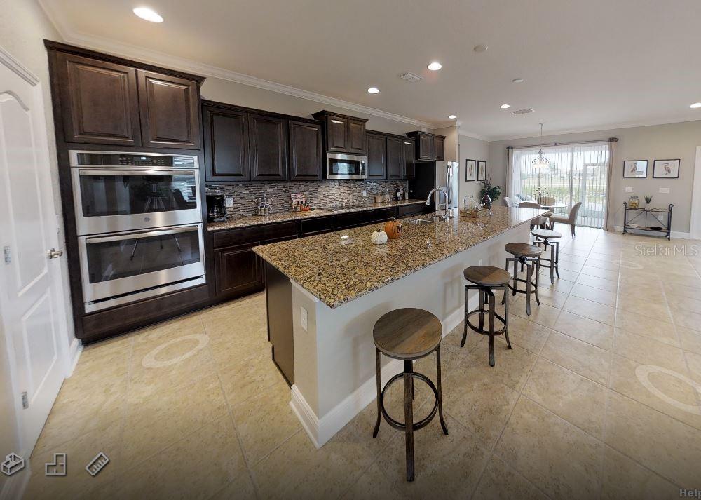 A kitchen with dark wood cabinets, granite countertops, a large island, and tile flooring — 6476 DUNBARTON STREET, NORTH PORT, FL