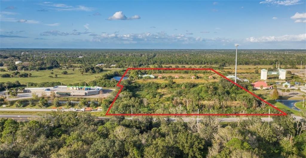An aerial view shows a vacant, tree-covered lot outlined in red next to a commercial building — 9555 Mesa Park Boulevard, Fellsmere FL 32948, FELLSMERE, FL