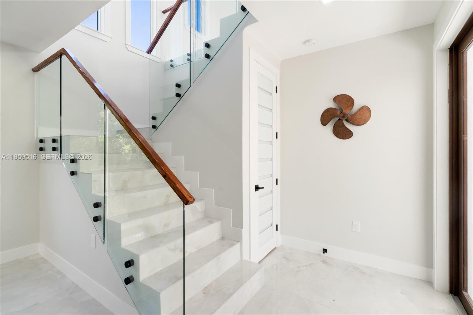 A modern staircase with glass railings and marble steps sits next to a white door — 862 Cardinal Ln, Key Largo FL 33037, KEY LARGO, FL