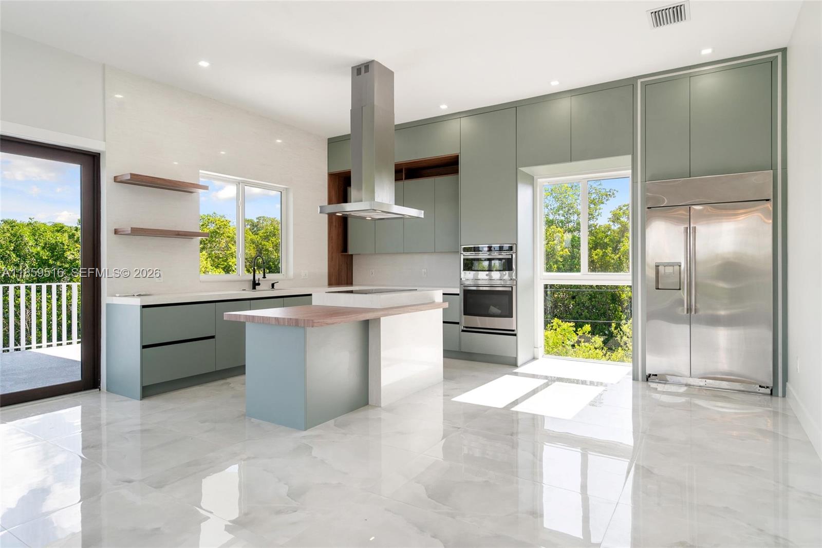 A modern kitchen features sage green cabinetry, a central island, stainless steel appliances, and marble flooring — 862 Cardinal Ln, Key Largo FL 33037, KEY LARGO, FL