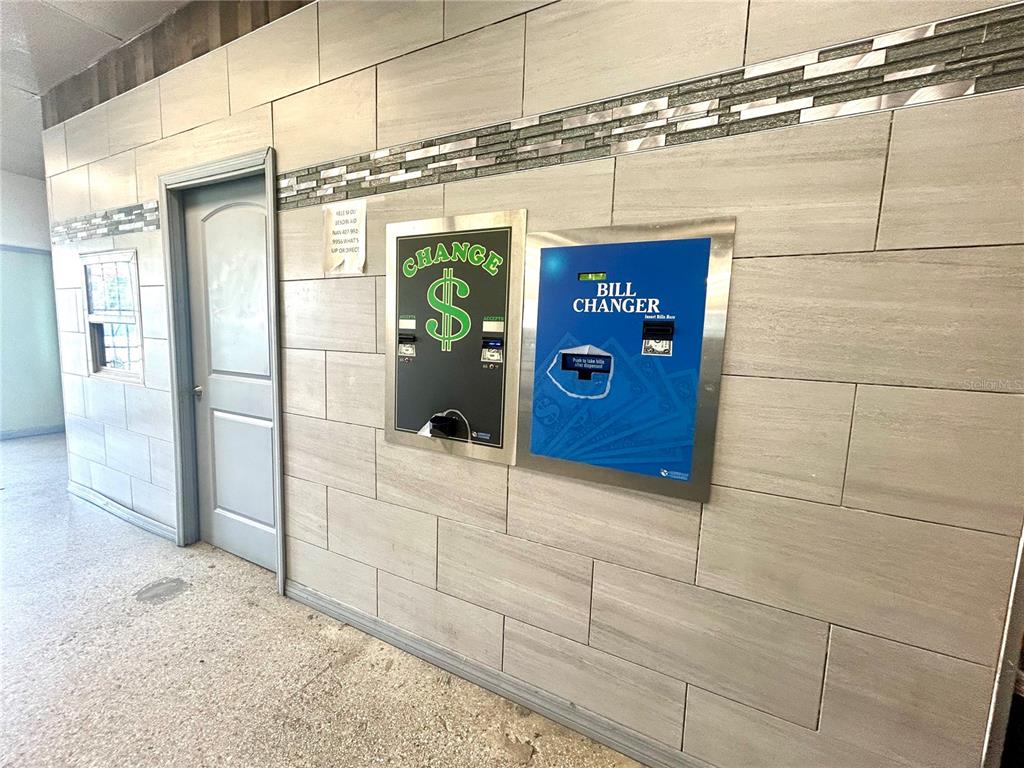 A tiled wall features a door, a small window, and two built-in bill changer machines — 2604 AVENUE V NW, WINTER HAVEN, FL